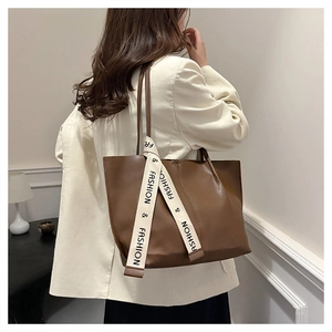 Detailaufnahme der braunen Leder-Tote-Bag mit modischem weißem Band mit Buchstabendruck