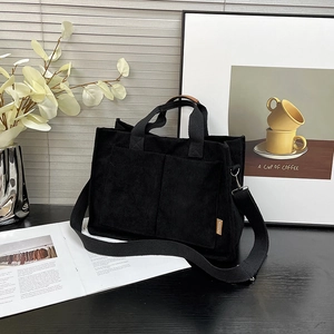 Minimalist black corduroy tote bag with dual front pockets and shoulder straps