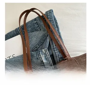 Detail showing dark brown corduroy tote bag with durable leather handles and zip closure