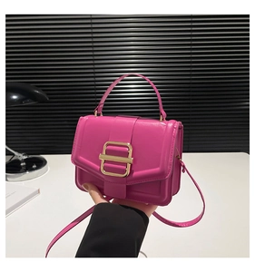 Detail of fuchsia square handbag with golden clasp and leather handle for women