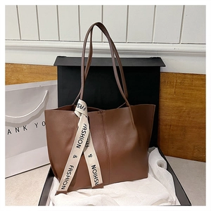 Detailansicht der braunen Leder-Tote-Bag mit vertikalen Nähten und modischem Band-Detail