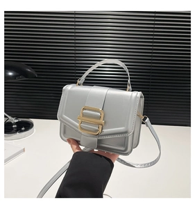 Detail of silver faux leather crossbody bag with metallic sheen and gold square buckle