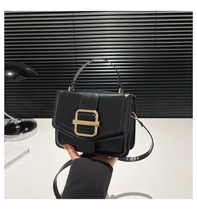 Close-up of black matte leather square bag with elegant gold rectangular metal buckle
