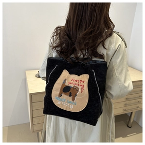 Detail of black corduroy tote bag featuring a cute cat patch and smiling face embroidery
