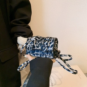 Detail of blue and black leopard print crossbody bag with silver buckles and flap closure