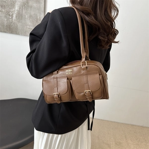 Brown leather boston bag with dual front pockets and shoulder strap shown on a model
