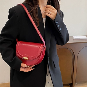 Borsa a sella rossa retrò con chiusura dorata indossata su un blazer nero elegante