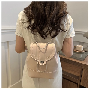 Detail of light pink faux leather backpack with silver turn-lock and chain strap on model