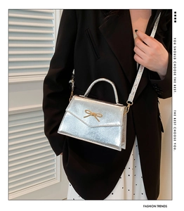 Détail d'un sac bandoulière argenté avec fini métallique miroir et nœud décoratif élégant