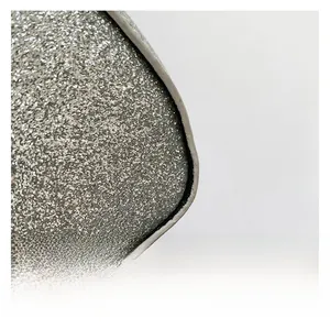 Detailed close-up of shiny silver glitter fabric and gray leather piping on a stylish handbag