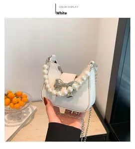 Close-up of white sequin saddle bag featuring pearl handle and silver bow detail