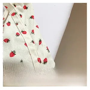 Detail shot of corduroy fabric with strawberry print showing soft vertical rib texture