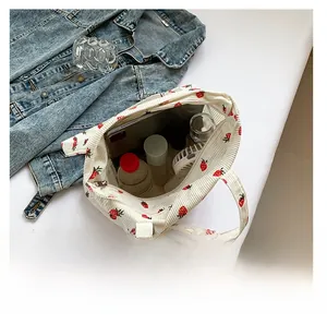 Spacious interior of strawberry print corduroy tote bag showing various personal items