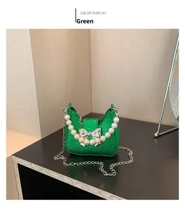 Detail of green glitter mini handbag with pearl handle and silver bow buckle