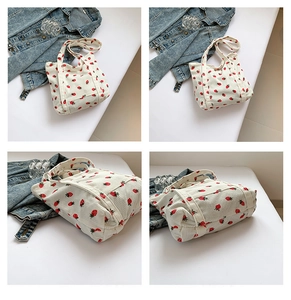 Detail view of corduroy tote bag featuring red strawberry print and soft ribbed texture
