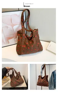 Detail of brown corduroy tote bag featuring red strawberry embroidery and soft texture