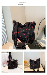 Detail of black corduroy tote bag with red strawberry embroidery and dual shoulder straps