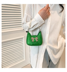 Detail of green sequin mini bag with gold bow, pearl handle and chain strap
