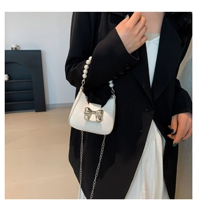 Mini-Perlentasche mit Glitzerleder und goldener Schleife an einem Model getragen