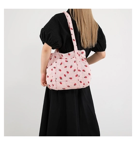 Close-up of pink corduroy tote bag featuring strawberry pattern and dual shoulder straps