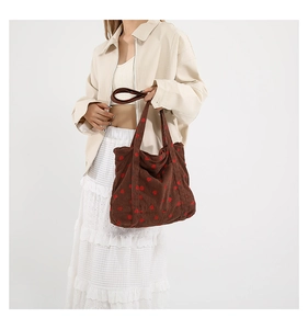 Detail of a large brown corduroy tote bag with red strawberry patterns and wide shoulder straps