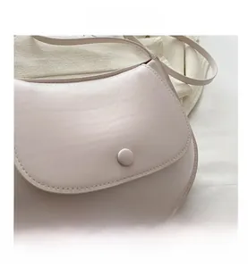 Close-up of the pastel leather saddle bag showing stitching and round buckle detail