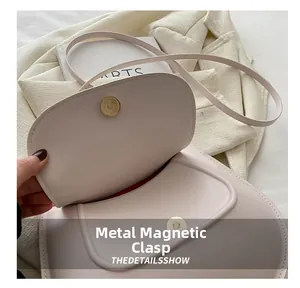 Close-up of the elegant magnetic closure on a beige leather saddle shoulder bag