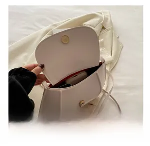 Detail show of creamy half-moon saddle bag interior with red lining and magnetic closure