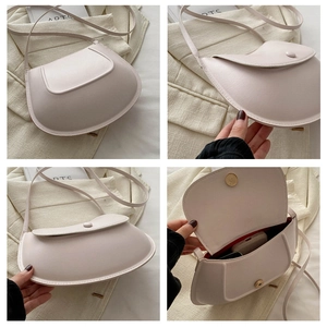 Detail view of the beige saddle bag showing its magnetic closure and internal capacity