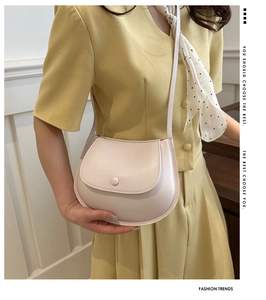 Detail of cream beige saddle bag featuring smooth leather texture and magnetic snap closure