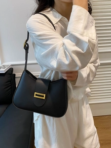 Classic black leather underarm bag with gold metal buckle shown on a model