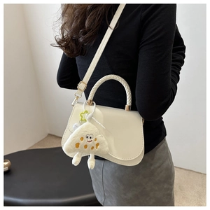 Detail of white PU crossbody bag featuring a woven handle and plush cartoon charm