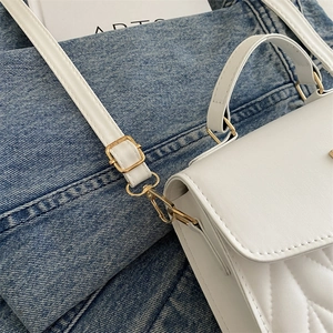 Close-up of white chevron quilted bag with premium gold-tone hardware and stitching