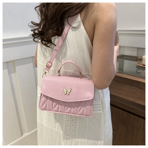 Pink crossbody bag with diamond quilted stitching and a metal butterfly buckle detail