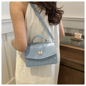 Light blue crossbody bag with butterfly clasp and quilted pattern shown on model