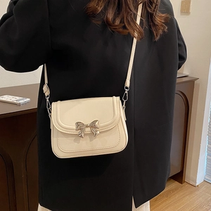 Elegante cremeweiße Umhängetasche mit silberner Metallschleife auf der Lederklappe