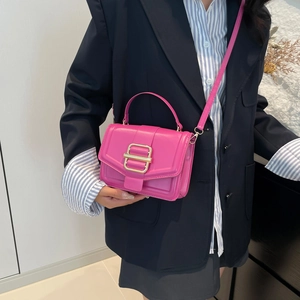 Chic magenta mini crossbody bag with gold buckle on blue navy suit fashion model