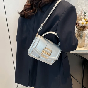 Minimalist silver metallic textured handbag with golden buckle worn with black blazer