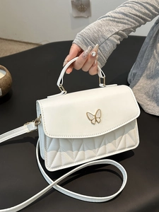 White macaron crossbody bag featuring quilted patterns and a gold butterfly clasp
