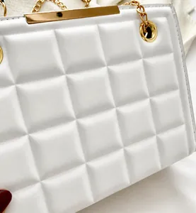 Detalle del bolso acolchado blanco con barra metálica dorada y elegante cadena