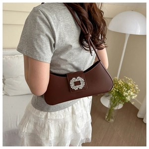 Gros plan d'un sac sous le bras marron foncé avec une boucle carrée en strass de luxe