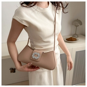 Détail du sac à bandoulière en cuir beige avec boucle en strass porté par un mannequin