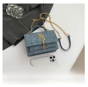 Detailed close-up of blue denim texture and gold metal logo on a crossbody bag