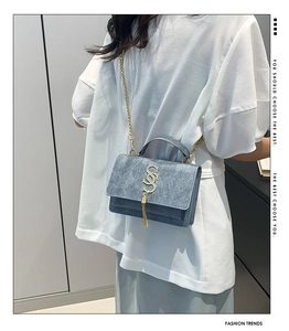 Detail view of light blue chain bag featuring gold metal hardware and tassel charm