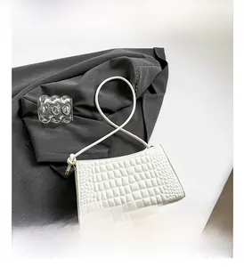 Close-up of white crocodile pattern faux leather texture on minimalist shoulder bag