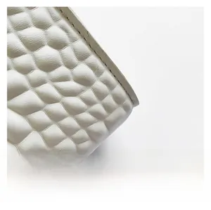 Close-up of white faux crocodile leather texture with premium black stitching detail