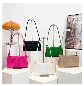 Five crocodile pattern underarm bags displayed in various colors on geometric stands