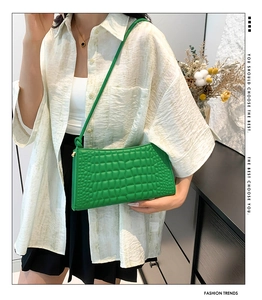 Detail of emerald green faux crocodile texture on a chic rectangular shoulder bag
