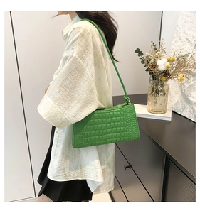 Close-up of a lime green crocodile pattern shoulder bag worn with a casual outfit
