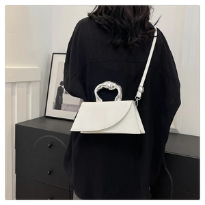 Detail of artistic silver wavy handle on a white minimalist geometric leather handbag
